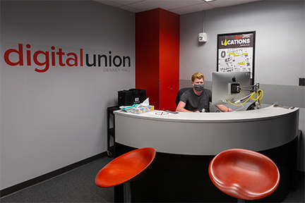 Student worker greeting from behind the front desk in the Denney Hall Digital Union.